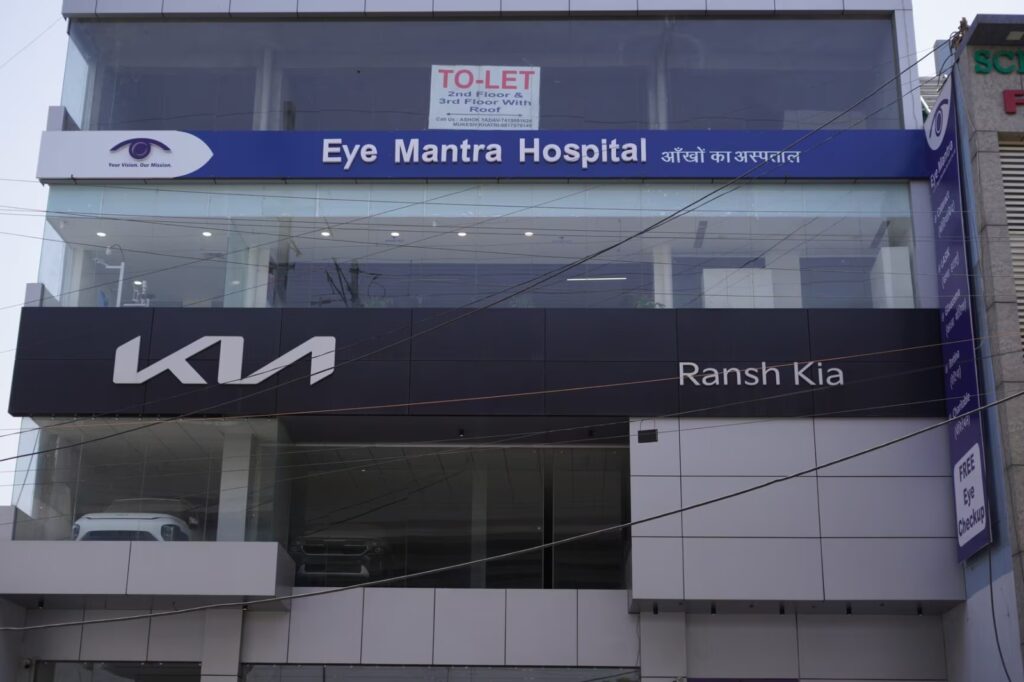 Front view of Eye Mantra Hospital Bahadurgarh above a KIA showroom building, offering expert optical and eye care services.