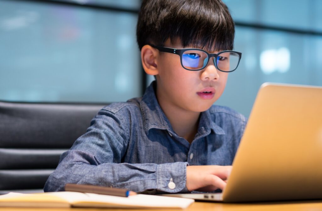 Boy wearing blue light glasses using laptop for study – Eye protection for students from screen glare